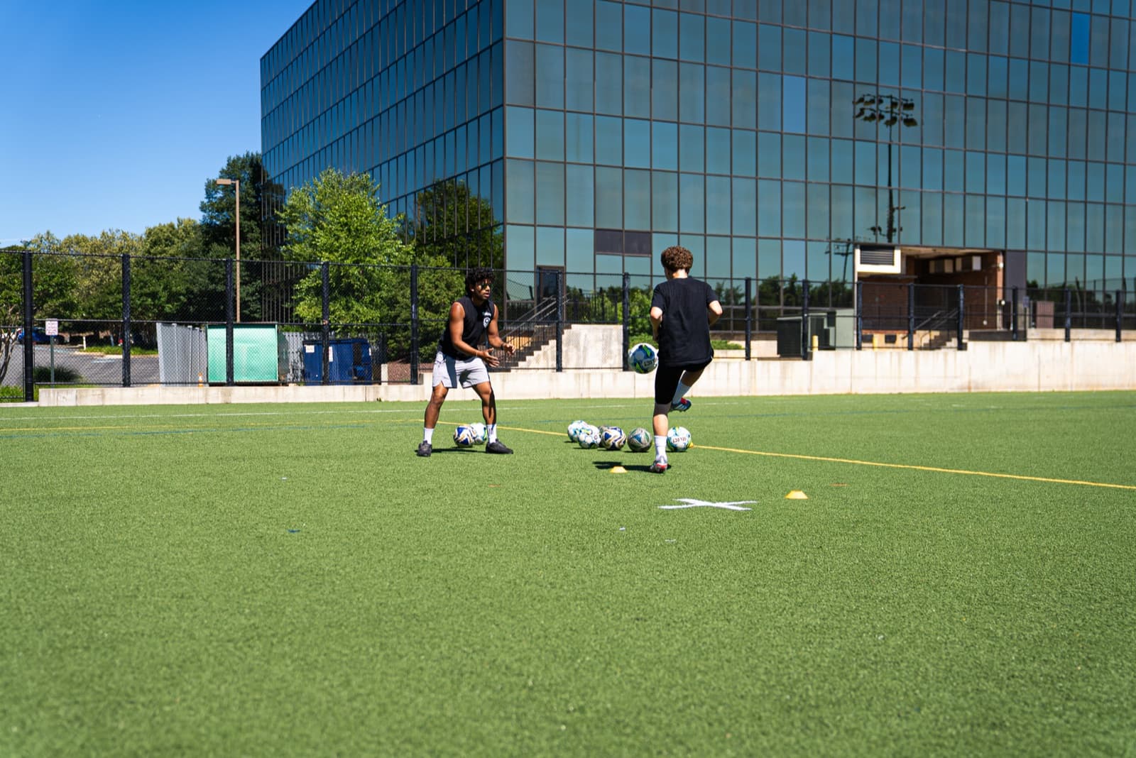 Tekne coach running a 1-on-1 first-touch drill on a turf field